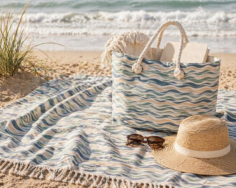 May include: A beach scene featuring a patterned tote bag, a straw hat, and sunglasses on a matching beach towel. The tote bag has rope handles and is filled with items. The towel and bag have a wave-like pattern in shades of blue, green, and tan.