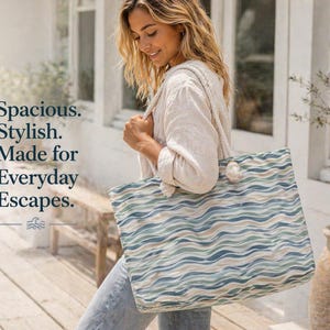 May include: A large tote bag with a wave pattern in shades of blue, green, and beige. The bag has rope handles and the text "Spacious. Stylish. Made for Everyday Escapes."