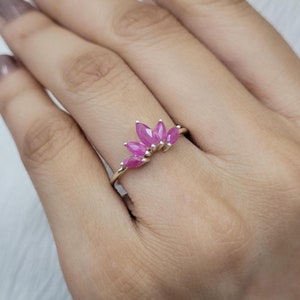 May include: A silver ring with a cluster of pink marquise-shaped gemstones set in a delicate band.
