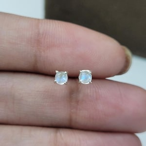 Puede incluir: Un par de pendientes de plata con piedras de luna redondas.