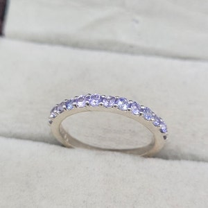 May include: A silver band ring with a row of small, light purple gemstones.