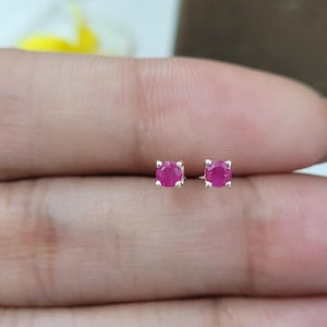 Puede incluir: Un par de pendientes de botón de plata con pequeñas piedras preciosas redondas de color rosa.