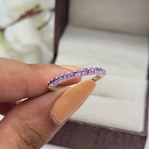 May include: A silver band ring with a row of small, round, purple gemstones.