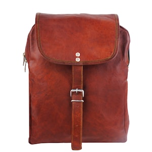 May include: A brown leather backpack with a flap closure and a buckle. The backpack has a rectangular shape with a zipper on the side. The leather has a textured appearance and is stitched with a contrasting thread.