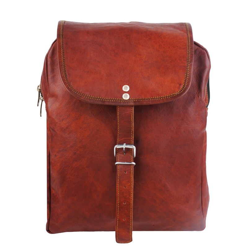 May include: A brown leather backpack with a flap closure and a buckle. The backpack has a rectangular shape with a zipper on the side. The leather has a textured appearance and is stitched with a contrasting thread.