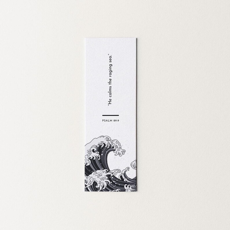 May include: A white bookmark featuring a black and white illustration of a wave. The text "He calms the raging sea." and "PSALM 89:9" are printed in black. The bookmark has a minimalist design.
