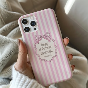 May include: A pink and white striped phone case with a bow and the text "The joy of the Lord is my strength. Nehemiah 8:10". The case has a camera cutout and a smooth finish.