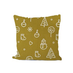 May include: Mustard-colored square pillow with a repeating white Christmas-themed pattern. The pattern includes line drawings of ornaments, snowflakes, trees, a snowman, and stockings. The pillow is a decorative item.