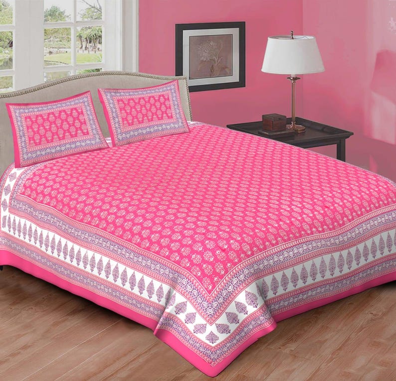 Peut inclure: Une parure de lit rose vif avec un motif blanc et violet r&eacute;p&eacute;t&eacute;. L'ensemble comprend un drap-housse et deux taies d'oreiller. La literie est pr&eacute;sent&eacute;e sur un lit dans une chambre rose. La bordure a un motif de feuilles.