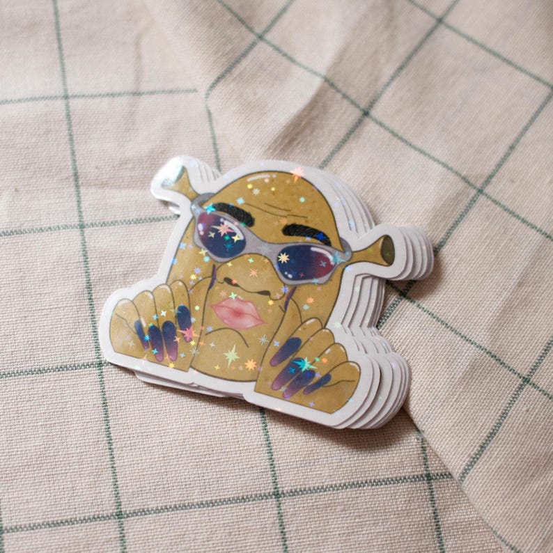 May include: A stack of stickers featuring a cartoon character with sunglasses, a pouty mouth, and long, blue fingernails. The character has a tan complexion and is covered in glitter. The stickers are die-cut with a white border.