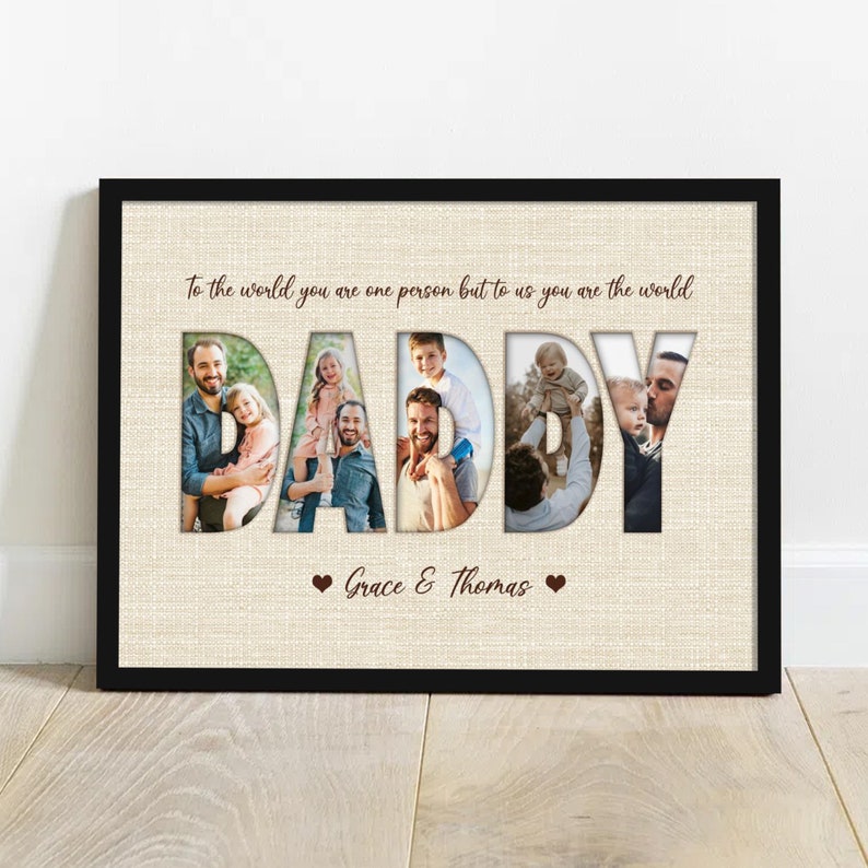 May include: A framed print with the word "DADDY" cut out to reveal family photos. The print has a beige background with the text "To the world you are one person but to us you are the world" and the names "Grace & Thomas".