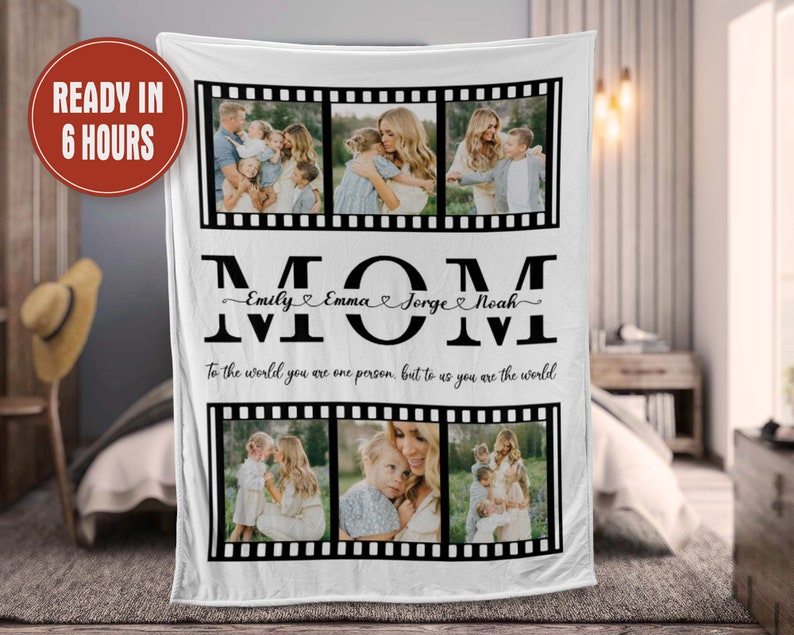 Op de afbeelding: Een wit fleece deken met een zwart-wit filmstripontwerp. Het deken heeft vier foto's van een vrouw met haar kinderen. De tekst "MOM" is geschreven in grote zwarte letters met de namen "Emily, Emma, Jorge, Noah" geschreven in cursief eronder. De tekst "To the world you are one person, but to us you are the world" is geschreven in zwart onder de namen.