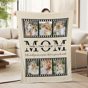 Op de afbeelding: Een beige fleece deken met een zwart-wit filmstripontwerp. De deken heeft vier foto's van een vrouw met haar kinderen. De tekst "MOM" is geschreven in grote zwarte letters met de namen "Emily, Emma, Jorge, Noah" in cursief eronder. De tekst "To the world you are one person, but to us you are the world" staat onder de namen.