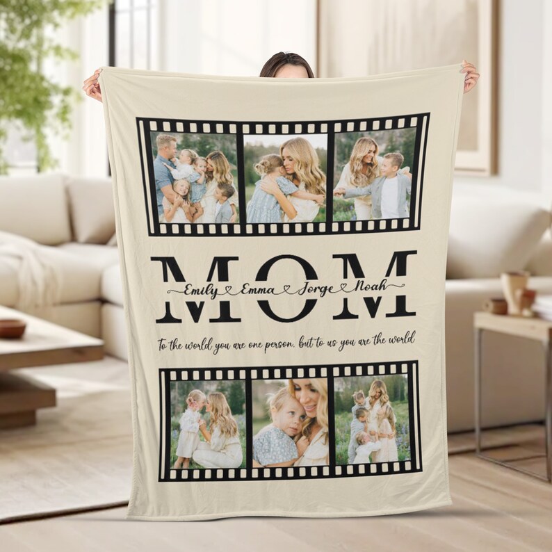 Op de afbeelding: Een beige fleece deken met een zwart-wit filmstripontwerp. De deken heeft vier foto's van een vrouw met haar kinderen. De tekst "MOM" is geschreven in grote zwarte letters met de namen "Emily, Emma, Jorge, Noah" in cursief eronder. De tekst "To the world you are one person, but to us you are the world" staat onder de namen.