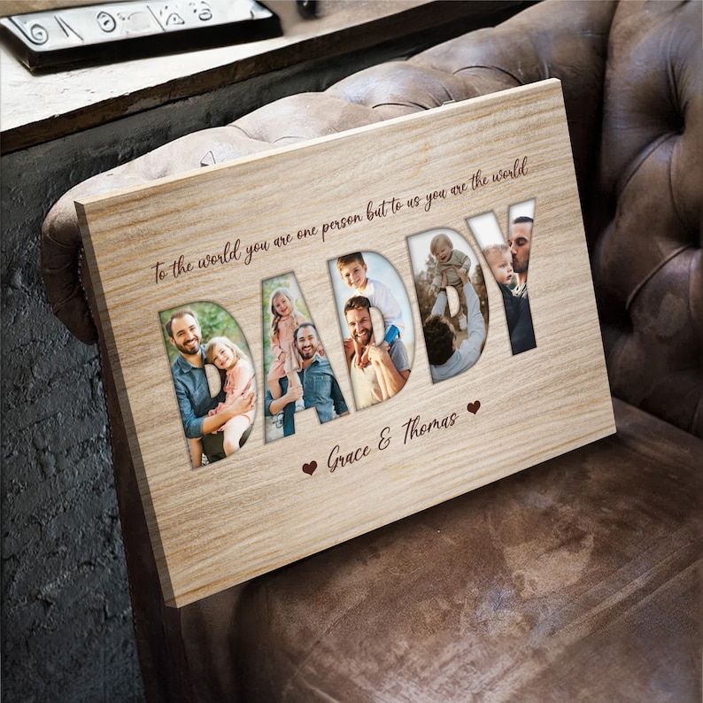 May include: Wooden photo plaque with the word "DADDY" cut out, revealing family photos. The plaque has the text "To the world you are one person but to us you are the world" and "Grace & Thomas" with heart symbols.