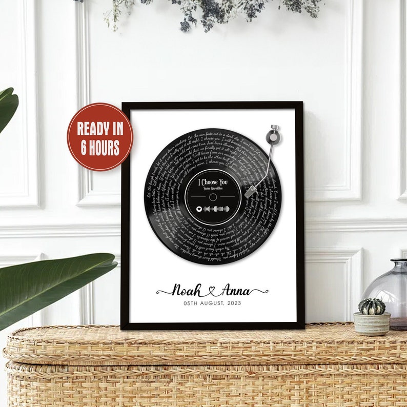 Pu&ograve; includere: Una stampa di un disco in vinile in bianco e nero con il testo della canzone "I Choose You" di Sara Bareilles. La stampa include un ago nero e un codice Spotify. La stampa &egrave; incorniciata in una cornice nera e ha i nomi "Noah & Anna" e la data "05th August, 2023" stampati sotto il disco.