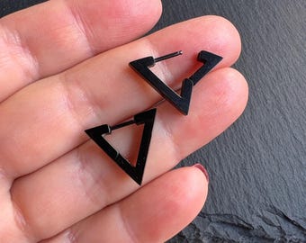 Puede incluir: Un par de pendientes de aro triangulares negros. Los pendientes están hechos de metal y tienen un diseño simple y geométrico.