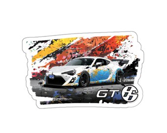May include: A white sports car sticker with blue and gold paint splatter details. The sticker has a black and white GT86 logo on the bottom right corner. The background features a colourful abstract design.