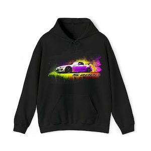 Puede incluir: Sudadera negra con un gráfico colorido de un Honda S2000 blanco con detalles morados. El coche está rodeado de un efecto de pintura en aerosol con colores amarillo, verde y rojo.