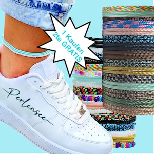 Könnte beinhalten: Weiße Turnschuhe mit dem Wort "Perlensee" in Schreibschrift. Ein hellblaues und weißes Fußkettchen wird am Knöchel getragen. Stapel bunter Armbänder werden neben dem Schuh angezeigt. Das Bild enthält den Text "1 Kaufen 2te GRATIS".