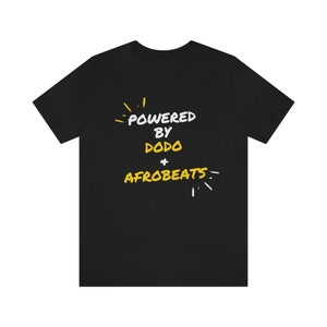 May include: Black t-shirt with white text that reads "Powered by Dodo + Afrobeats". The text is surrounded by yellow stylized starbursts.