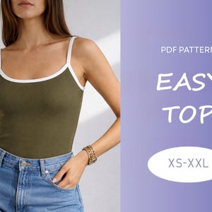 May include: An olive green tank top with white trim and spaghetti straps. The text "EASY TOP" is displayed in white, along with "XS-XXL" in a white oval. The model is wearing blue jeans and a gold bracelet.