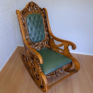 May include: A wooden rocking chair with intricate carvings and a green upholstered seat. The chair has a high back and curved arms.