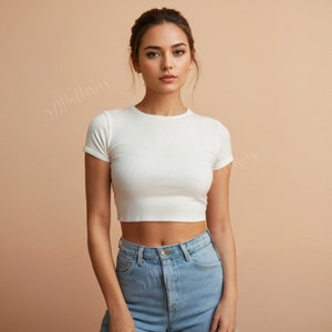 May include: A woman wearing a white cropped t-shirt and light blue jeans.