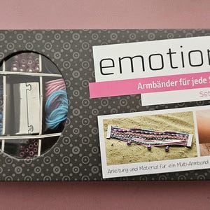 Könnte beinhalten: Eine Box mit einem Emotions-Freundschaftsarmband-Bastelset. Die Box zeigt ein Bild eines Armbands an einem Sandstrand und eine Nahaufnahme der Perlen und Fäden, die im Set enthalten sind. Auf der Box steht "emotions Armbänder für jede Stimmung Set Friendship".
