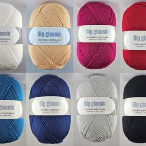 Könnte beinhalten: Acht Wollknäuel in verschiedenen Farben: Weiß, Beige, Fuchsia, Rot, Blau, Marine, Grau und Schwarz. Jedes Knäuel hat ein Etikett mit der Aufschrift "Big Classic UNIVERSALSTRICKGARN".