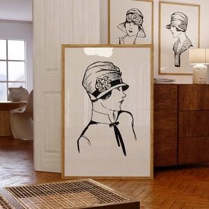 May include: Three black and white framed illustrations of women wearing hats. The illustrations are in a minimalist style and feature simple lines and shapes. The illustrations are hanging on a white wall.