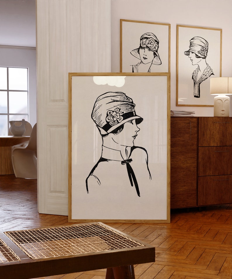 May include: Three black and white framed illustrations of women wearing hats. The illustrations are in a minimalist style and feature simple lines and shapes. The illustrations are hanging on a white wall.