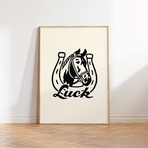 May include: Black and white illustration of a horse's head inside a horseshoe with the word "Luck" written below.