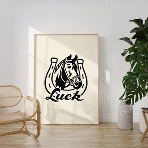 May include: Black and white illustration of a horse's head inside a horseshoe with the word "Luck" printed below.