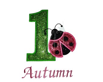 May include: Green glitter number one with a pink and black ladybug on the right side. The word "Autumn" is written in pink below the number.