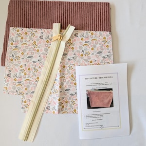 May include: A sewing kit with a floral patterned fabric, a mauve corduroy fabric, and a beige zipper. The kit includes a printed instruction sheet with the text "KIT COUTURE / TROUSSE ELISA".