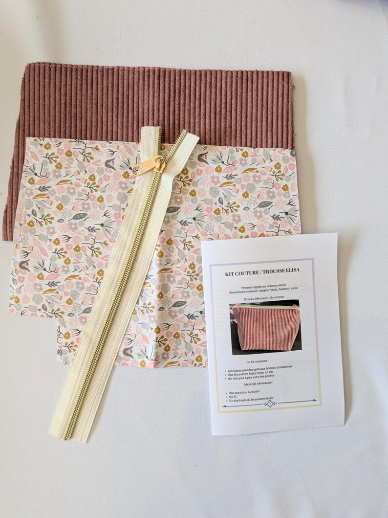 May include: A sewing kit with a floral patterned fabric, a mauve corduroy fabric, and a beige zipper. The kit includes a printed instruction sheet with the text "KIT COUTURE / TROUSSE ELISA".