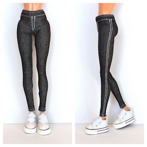 May include: Black denim leggings with white stitching detail. The leggings are shown on a doll wearing white sneakers.