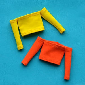 May include: Two off-the-shoulder tops, one yellow and one orange, on a blue background.