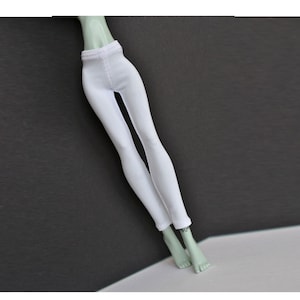 May include: White leggings for a doll, made of a stretchy fabric. The leggings are plain and have a simple design.