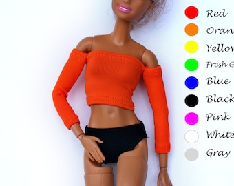 May include: A doll wearing an orange off-the-shoulder top with long sleeves and black shorts.