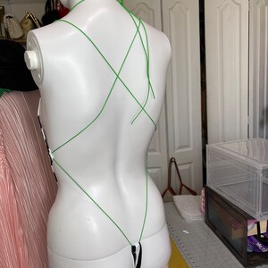 May include: A black and white striped bodysuit with a green string halter top. The straps are crisscrossed in the back.