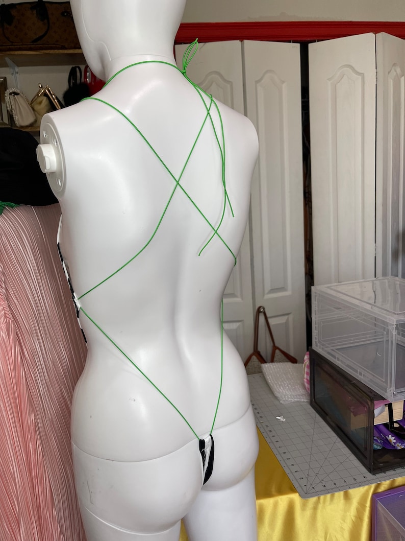 May include: A black and white striped bodysuit with a green string halter top. The straps are crisscrossed in the back.