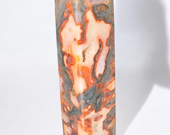 May include: A tall, pointed, orange, white, and gray agate crystal.
