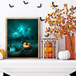 Puede incluir: Una impresión enmarcada con temática de Halloween con una calabaza tallada en una carretilla, una casa espeluznante en el fondo y una luna llena en el cielo. La impresión está en una repisa blanca con una calabaza blanca, una linterna y un jarrón de hojas de otoño.