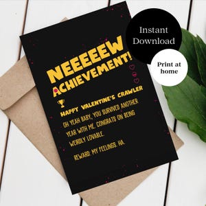 May include: A black greeting card with yellow text reading "NEEEEEEW ACHIEVEMENT!". The card features the phrases "HAPPY VALENTINE'S CRAWLER" and "OH YEAH BABY, YOU SURVIVED ANOTHER YEAR WITH ME." It rests on a brown envelope.