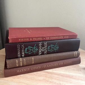 Puede incluir: Una pila de libros antiguos en varios colores. El libro superior es de color rojo oscuro, seguido de un libro morado oscuro con ilustraciones. Los títulos y nombres de los autores son visibles en los lomos.