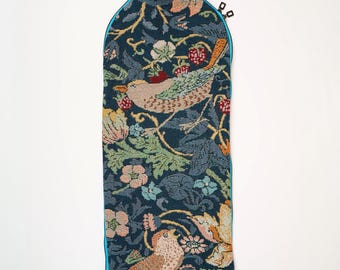 May include: A tall, cylindrical fabric wine bottle carrier featuring a dark blue tapestry background with a woven pattern of birds, strawberries, and floral foliage. It includes a dark blue top handle and a side zipper closure with two metal pulls.