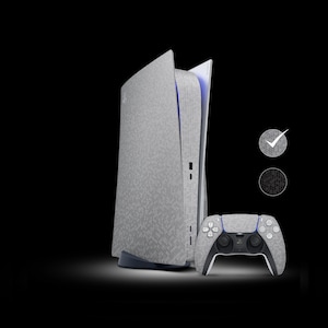 Puede incluir: Una consola PlayStation 5 blanca y gris con un mando a juego. La consola tiene un acabado texturizado, similar a la tela.