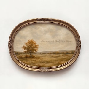Puede incluir: Un marco ovalado y ornamentado de tono dorado que contiene una pintura de paisaje de un campo con un solo árbol de follaje otoñal naranja. El cielo está nublado y el texto "autumn reminds us that beauty lies in letting go" está impreso.